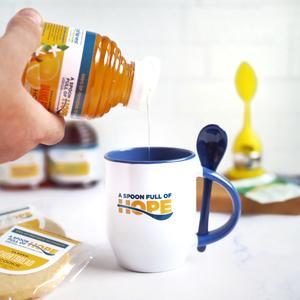 A Spoon Full of Hope honey poured into logo mug